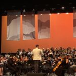 Maestro e orquestra durante apresentação no palco