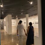 casal de mãos dadas caminha pela exposição de fotos