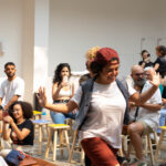 Artista se apresenta sorridente e passa caminhando entre as crianças