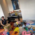 criança brinca sobre tapete de EVA com vários brinquedos espalhados.