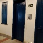placa ao lado de porta azul de madeira no auditório da FUMCULT