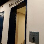 Porta de entrada da Rádio Educativa com placa em metal e braille na parede à direita