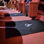 Detalhes de duas demarcações em preto para cadeira de rodas sobre piso vermelho, na sala de cinema.