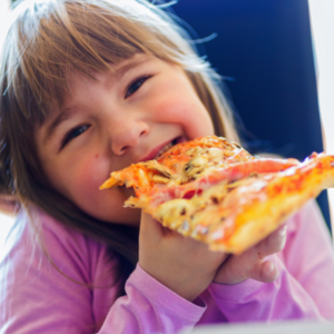 Foto de criança loira comendo fatia de pizza